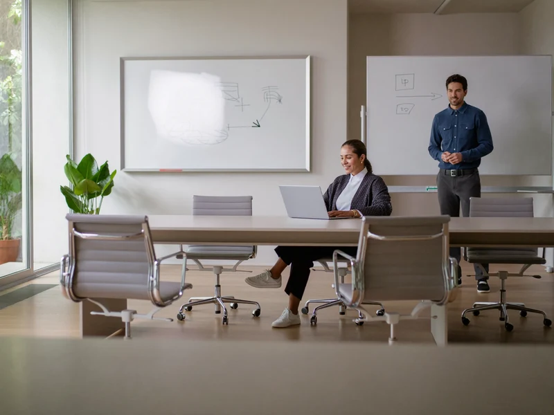 Salle de formation lumineuse où des adultes travaillent sur ordinateur autour d'un formateur